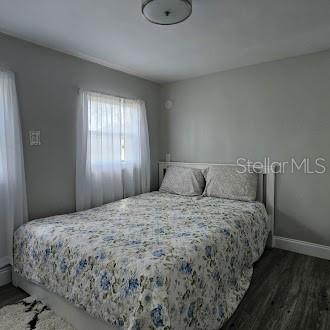 A bedroom features a bed with a floral comforter, gray walls, and wood-look flooring — 7127 W GROVER CLEVELAND BOULEVARD UNIT 48, HOMOSASSA, FL