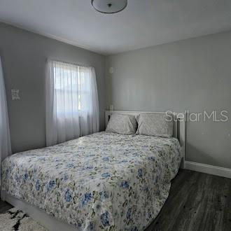 A bedroom features gray walls, wood-look flooring, a bed with a floral quilt, and white curtains — 7127 W GROVER CLEVELAND BOULEVARD UNIT 48, HOMOSASSA, FL