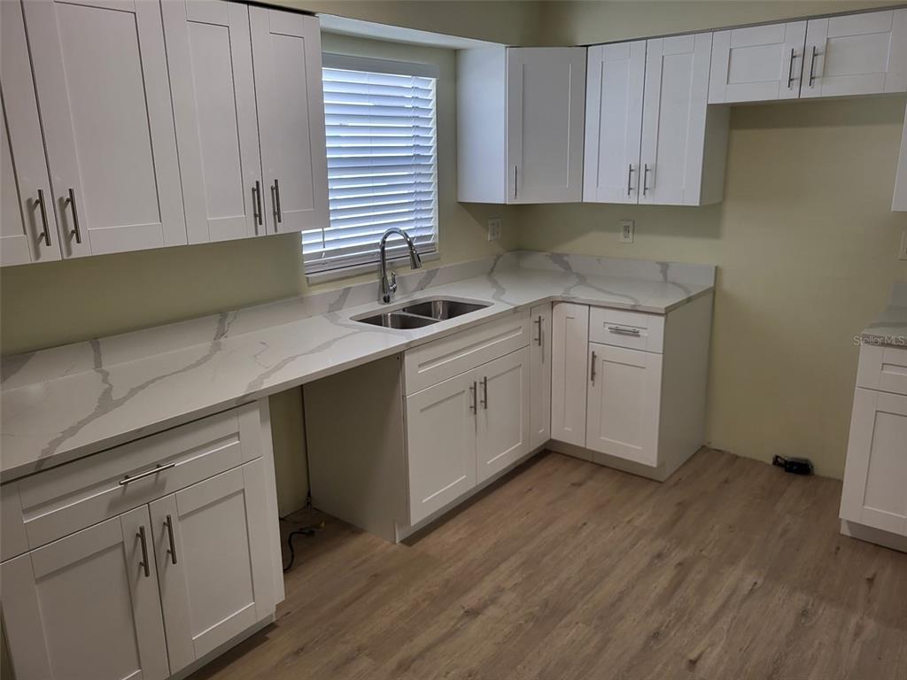 A kitchen features white shaker cabinets, quartz countertops, and light wood-look flooring — 5563 58TH STREET N, KENNETH CITY, FL