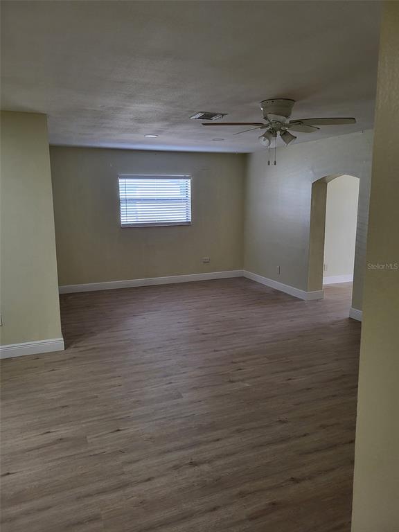 An empty room features light-colored wood-look flooring, pale yellow walls, and a ceiling fan — 5563 58TH STREET N, KENNETH CITY, FL