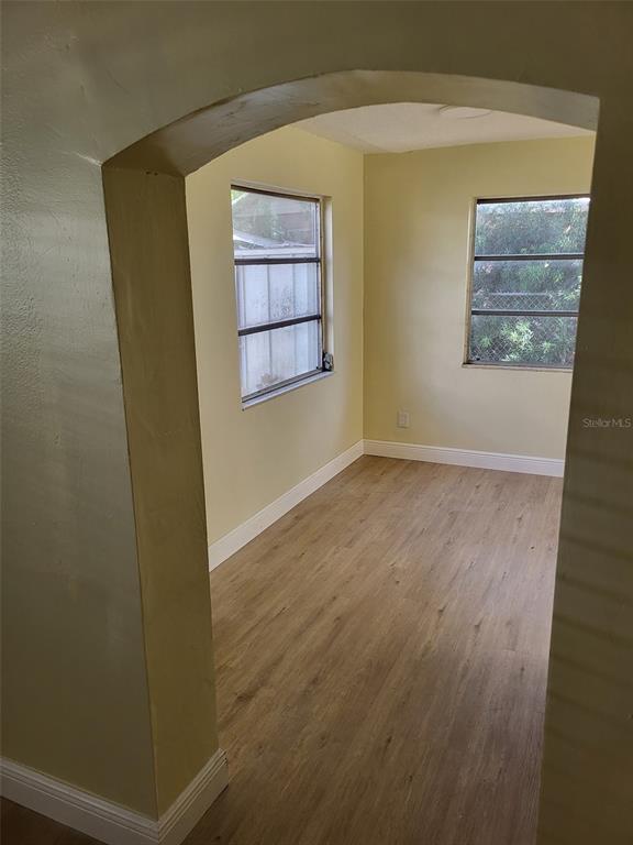 An arched doorway leads into a small room with light yellow walls and wood-look flooring — 5563 58TH STREET N, KENNETH CITY, FL
