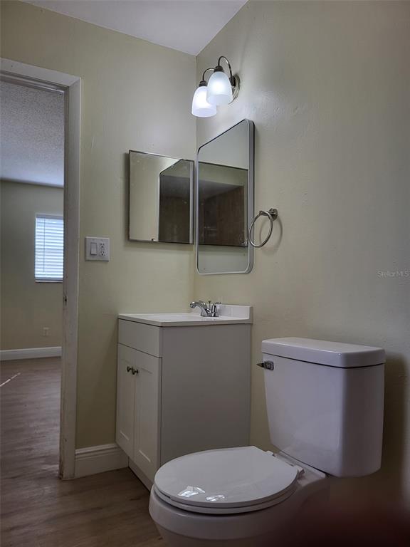 A bathroom features a white vanity with a sink, a toilet, and two wall mirrors — 5563 58TH STREET N, KENNETH CITY, FL