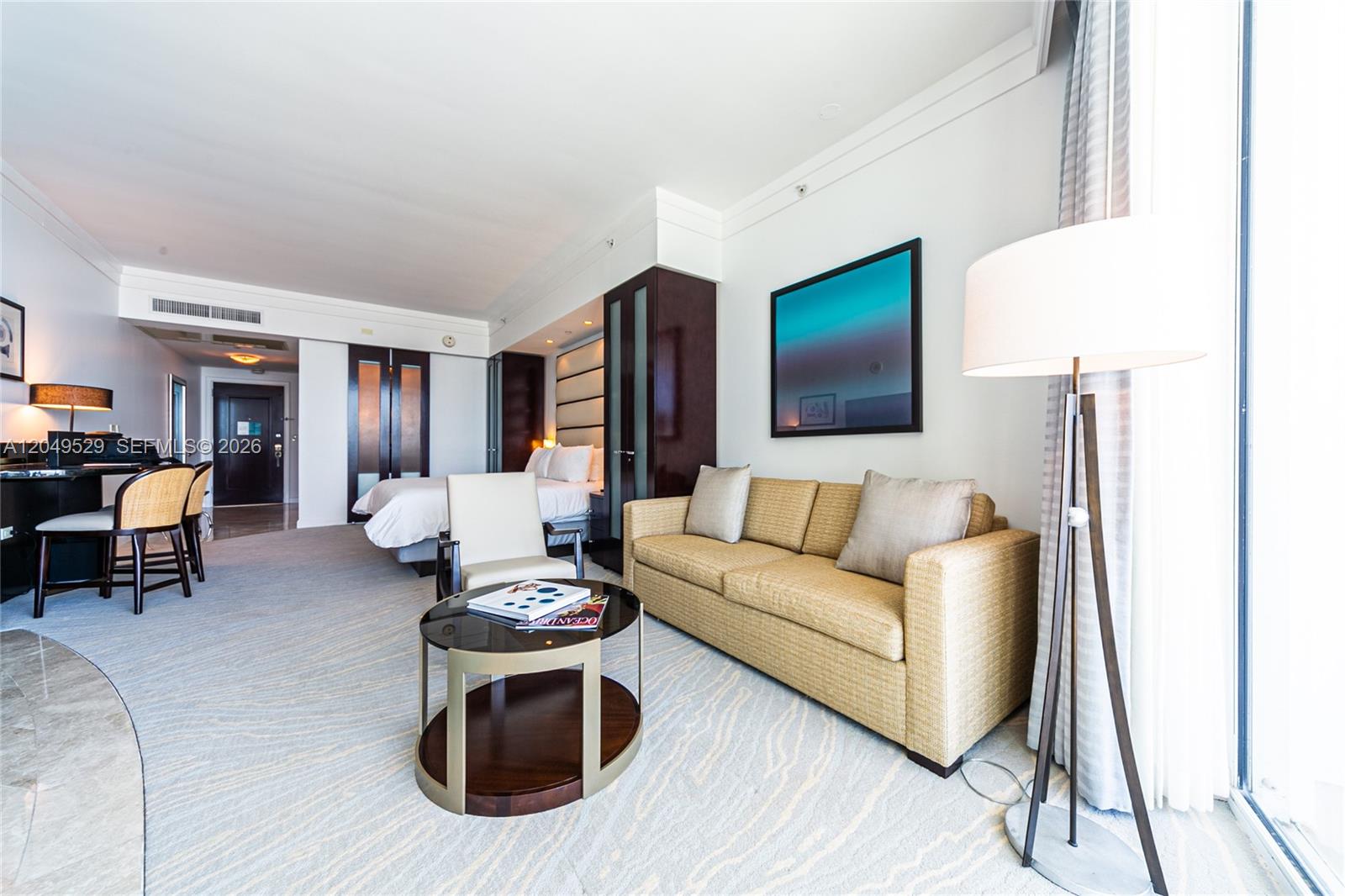 A hotel room features a sofa, a coffee table, a bed, and a floor lamp — 4391 Collins Ave # 1015, Miami Beach FL 33140, MIAMI BEACH, FL