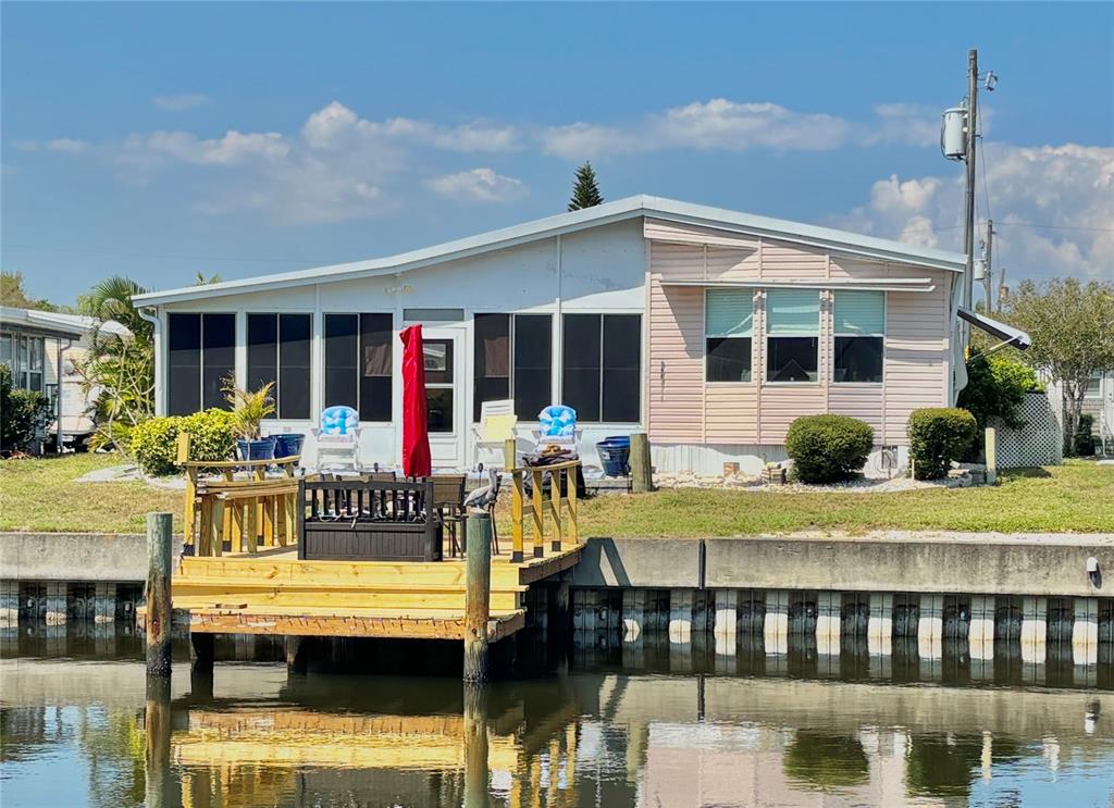 A waterfront mobile home features a wooden deck and a screened-in porch — 102 AMERICANA COURT NE UNIT 206, ST PETERSBURG, FL