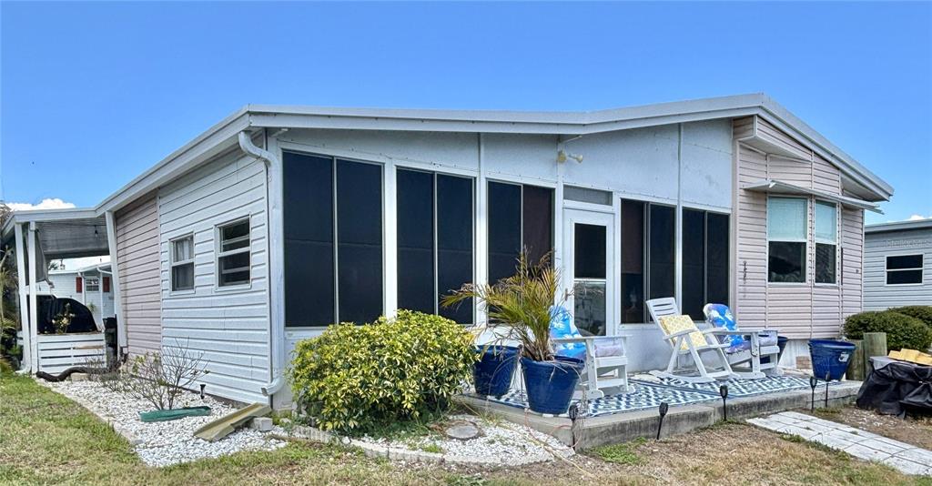 The exterior of a manufactured home features a screened-in porch and a concrete patio — 102 AMERICANA COURT NE UNIT 206, ST PETERSBURG, FL