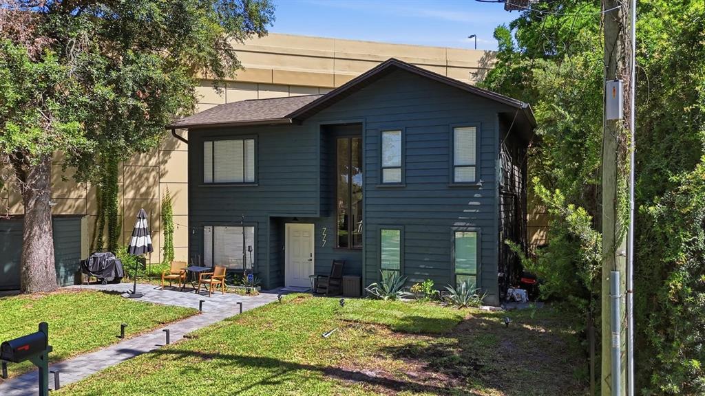A two-story house with dark siding, a white front door, and a paved patio area — 777 28TH STREET, ORLANDO, FL