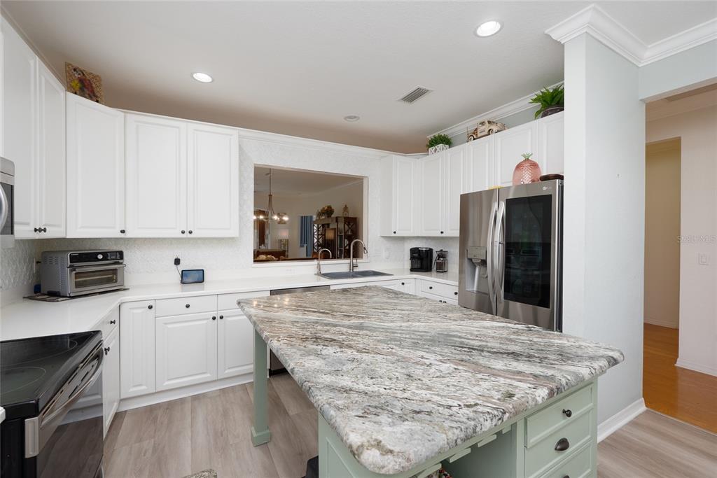 A kitchen features white cabinets, a granite-topped island, and stainless steel appliances — 2472 COTTONWOOD LANE, NORTH PORT, FL