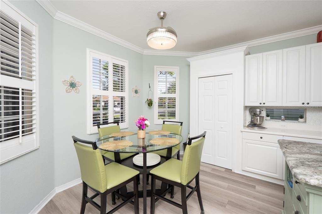 A dining nook features a glass-topped table, four green chairs, and white cabinetry — 2472 COTTONWOOD LANE, NORTH PORT, FL