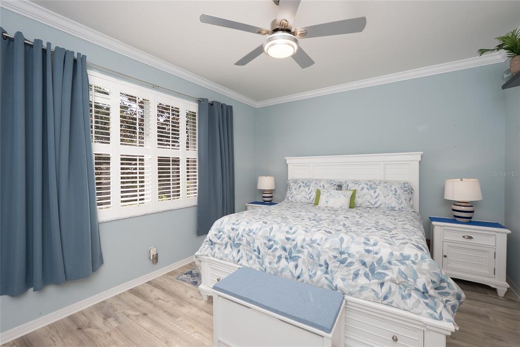 A bedroom features light blue walls, a white bed frame, and blue curtains over shutters — 2472 COTTONWOOD LANE, NORTH PORT, FL