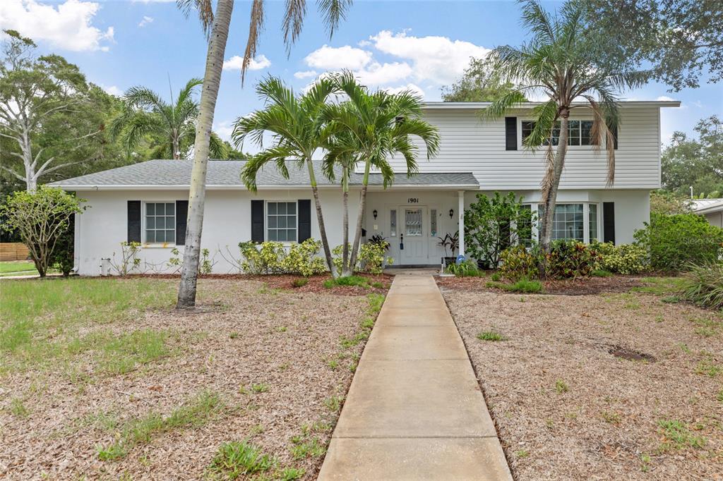 A two-story white house with black shutters and a palm-lined front walkway — 1901 DORMIEONE ROAD N, ST PETERSBURG, FL