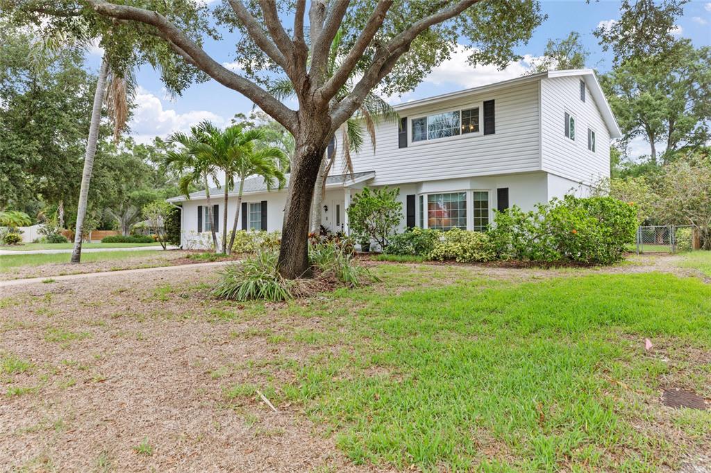 A two-story white house with black shutters and a large tree in the front yard — 1901 DORMIEONE ROAD N, ST PETERSBURG, FL