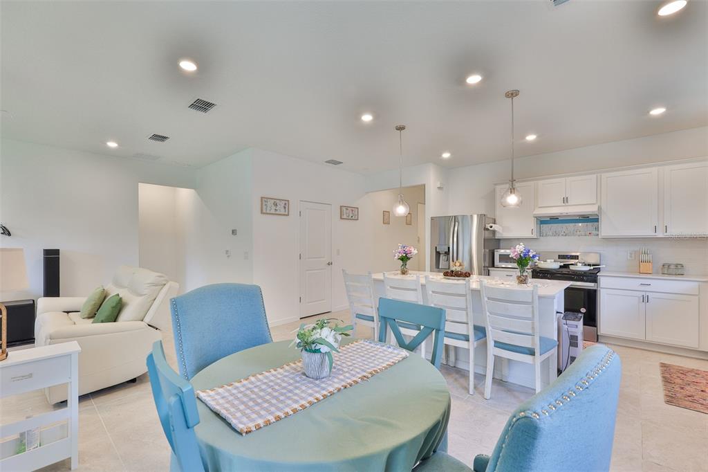An open-concept kitchen and dining area features white cabinetry, a central island, and blue chairs — 2948 FOREST MEADOW AVENUE, VALRICO, FL