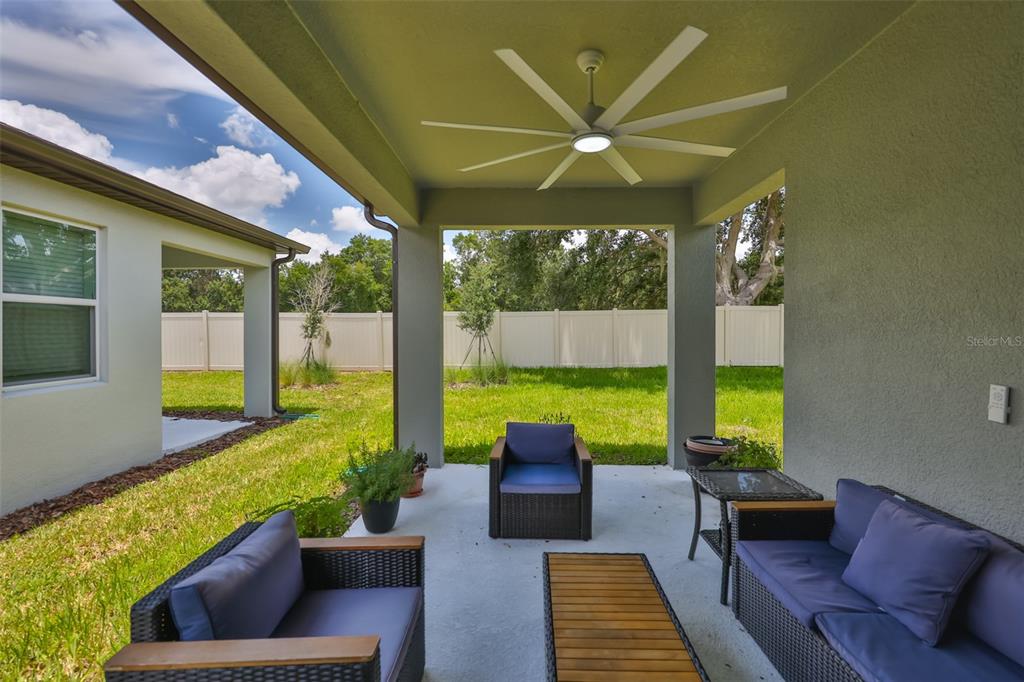 A covered patio features wicker furniture, a ceiling fan, and a view of the backyard — 2948 FOREST MEADOW AVENUE, VALRICO, FL