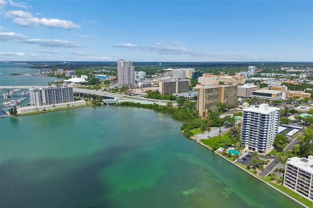 An aerial view shows a coastal city skyline with high-rise buildings, a bridge, and water — 80 ROGERS STREET UNIT 6C, CLEARWATER, FL