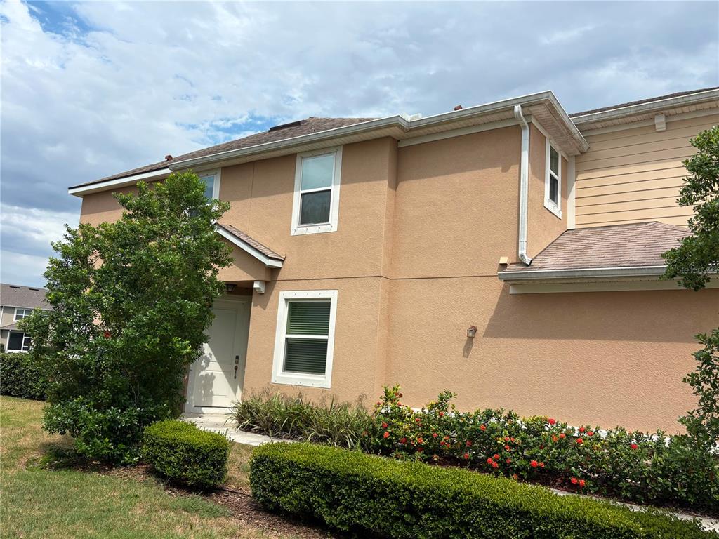A two-story tan stucco house exterior features a front entrance, windows, and landscaped bushes — 5553 PLEASANTVIEW COURT, BRADENTON, FL