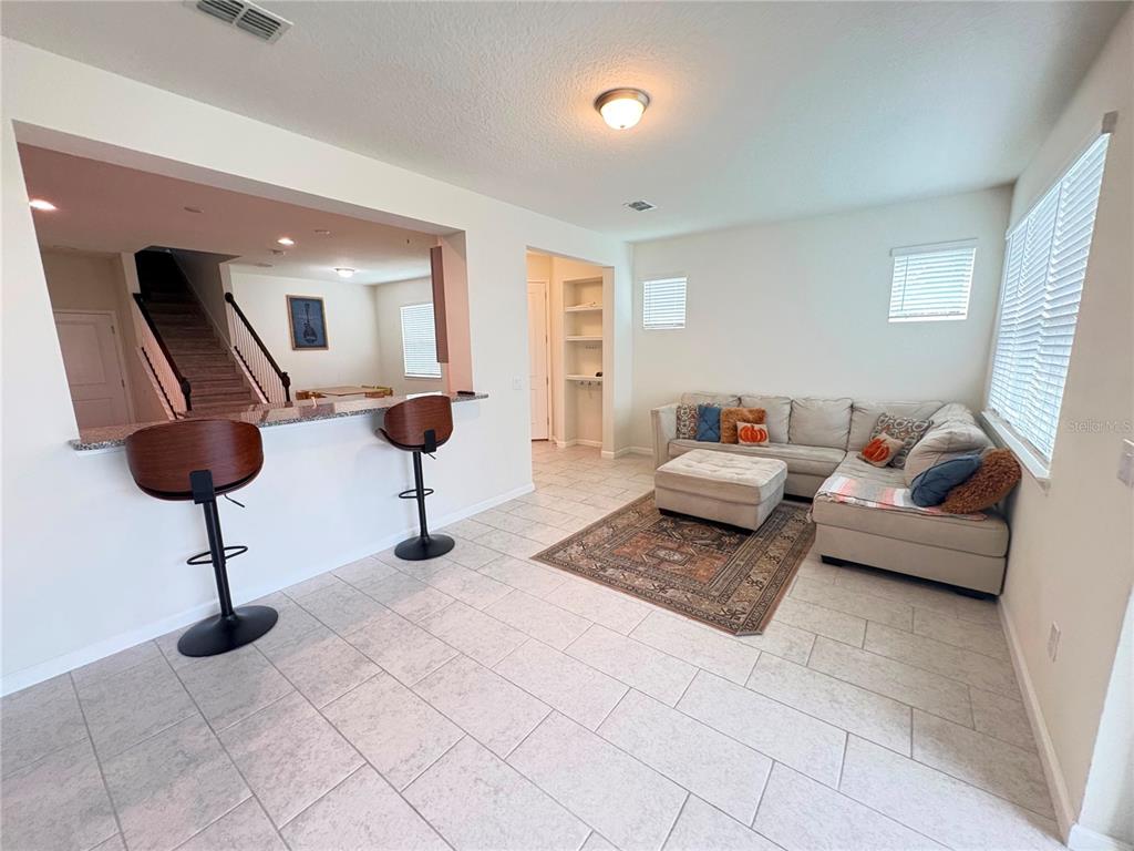 A living room with a sectional sofa, area rug, and a breakfast bar with stools — 5553 PLEASANTVIEW COURT, BRADENTON, FL