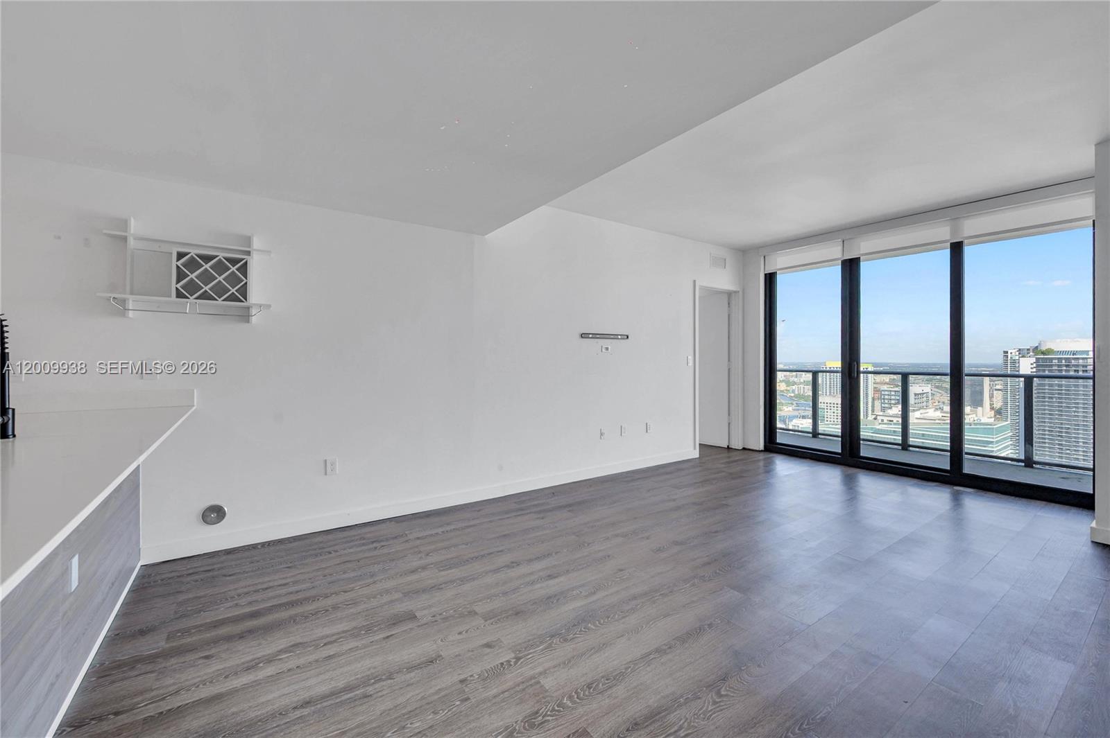 An empty living room features wood-look flooring, white walls, and floor-to-ceiling windows with city views — 1300 S Miami Ave # 4711, Miami FL 33130, MIAMI, FL