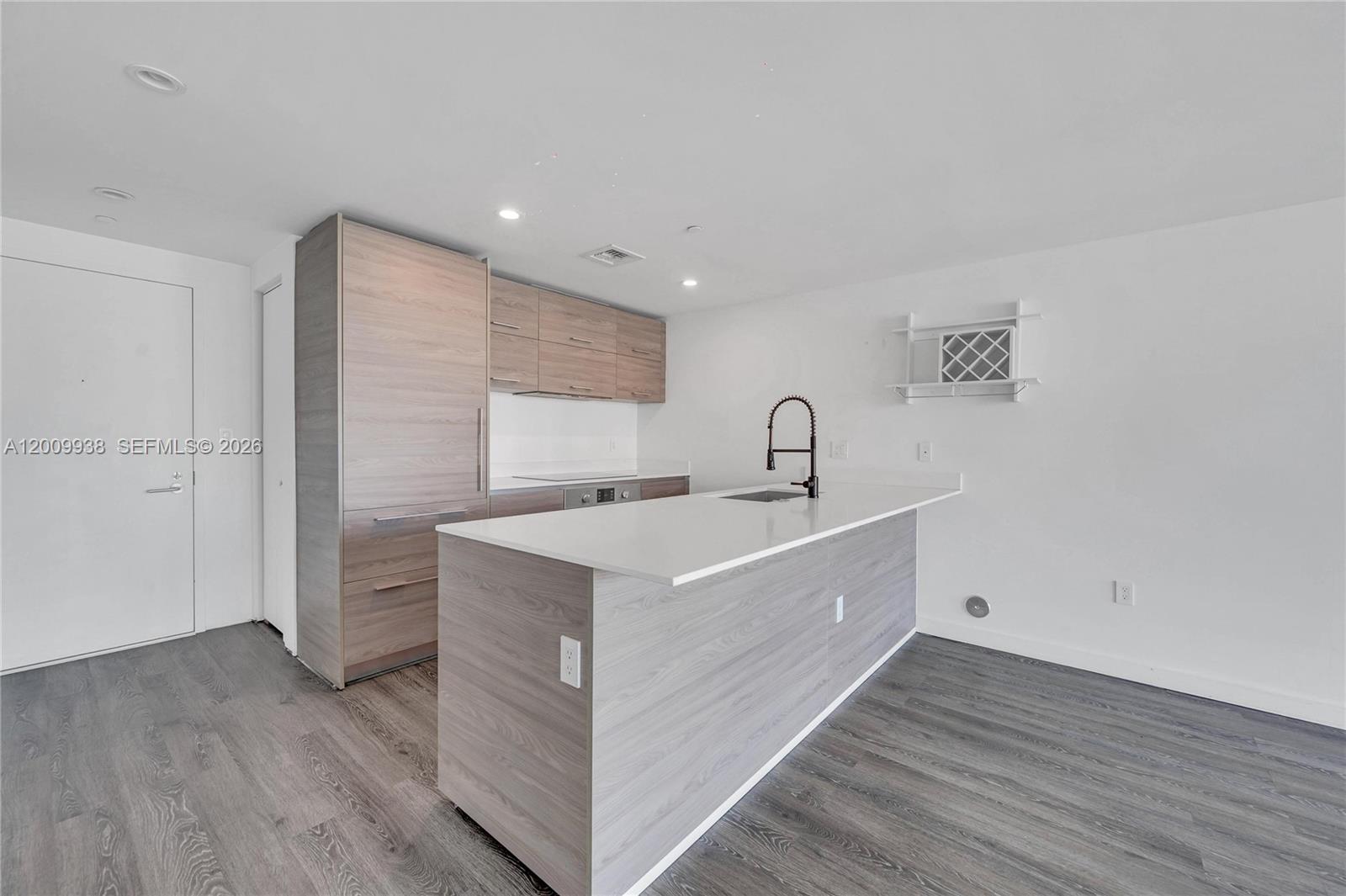 A modern kitchen features wood-grain cabinetry, a white quartz island, and dark wood-look flooring — 1300 S Miami Ave # 4711, Miami FL 33130, MIAMI, FL