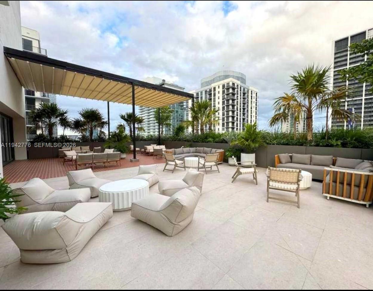 A spacious outdoor rooftop terrace features multiple seating areas, lounge chairs, and a retractable canopy — 601 N Miami Ave # 901, Miami FL 33316, MIAMI, FL