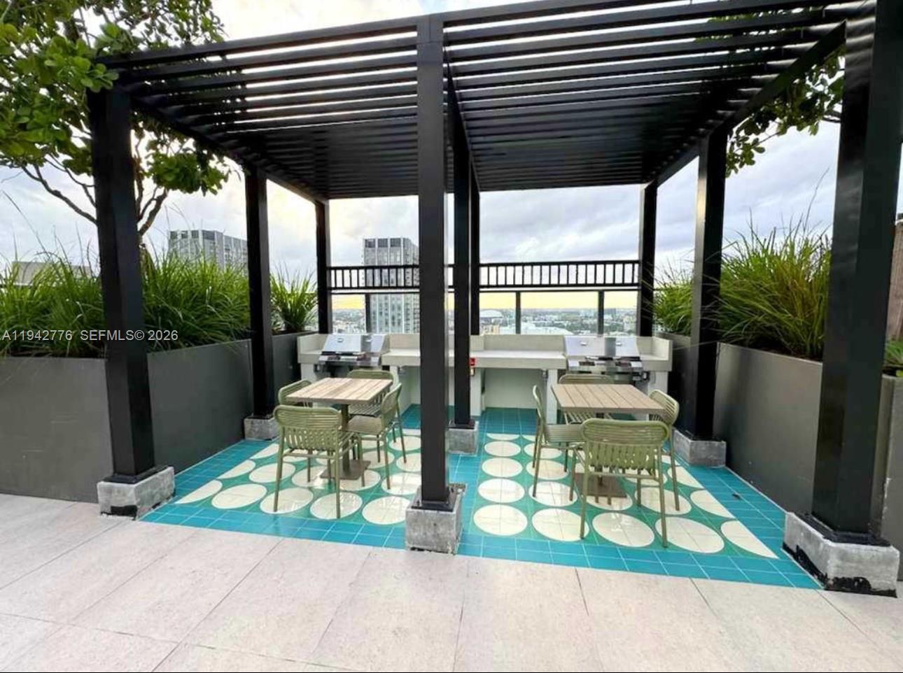An outdoor rooftop terrace features two grilling stations, dining tables, and a black pergola — 601 N Miami Ave # 901, Miami FL 33316, MIAMI, FL