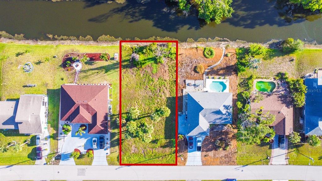 An aerial view shows a vacant rectangular lot situated between two houses near a canal — 22 MARK TWAIN LANE, ROTONDA WEST, FL