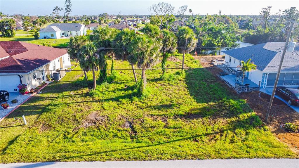 An elevated view of a vacant, grassy residential lot situated between two suburban houses — 22 MARK TWAIN LANE, ROTONDA WEST, FL