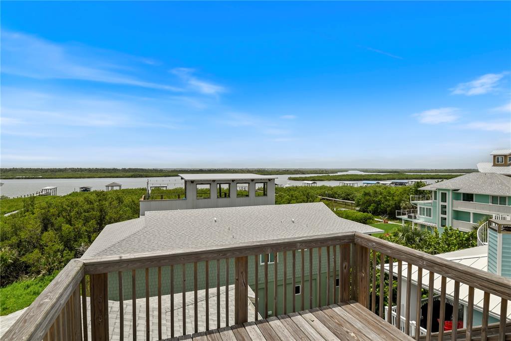 An elevated wooden deck overlooks a coastal landscape with houses, mangroves, and a waterway — 6956 TURTLEMOUND ROAD, NEW SMYRNA BEACH, FL