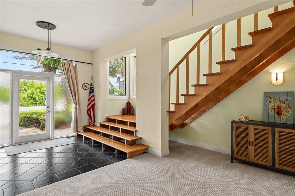 An entryway features a tiled floor, a wooden staircase, and a small set of wooden steps — 6956 TURTLEMOUND ROAD, NEW SMYRNA BEACH, FL