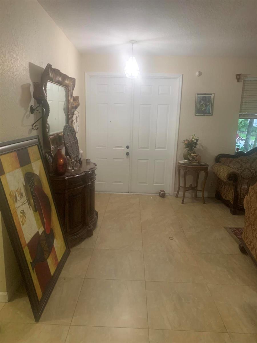 A tiled entryway features double white doors, a dark wood console table, and a mirror — 433 Gazetta Way, West Palm Beach FL 33413, WEST PALM BEACH, FL
