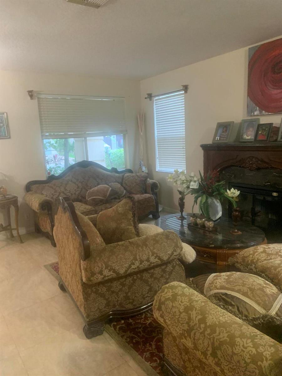 A living room features traditional patterned furniture, a marble-topped coffee table, and a fireplace — 433 Gazetta Way, West Palm Beach FL 33413, WEST PALM BEACH, FL