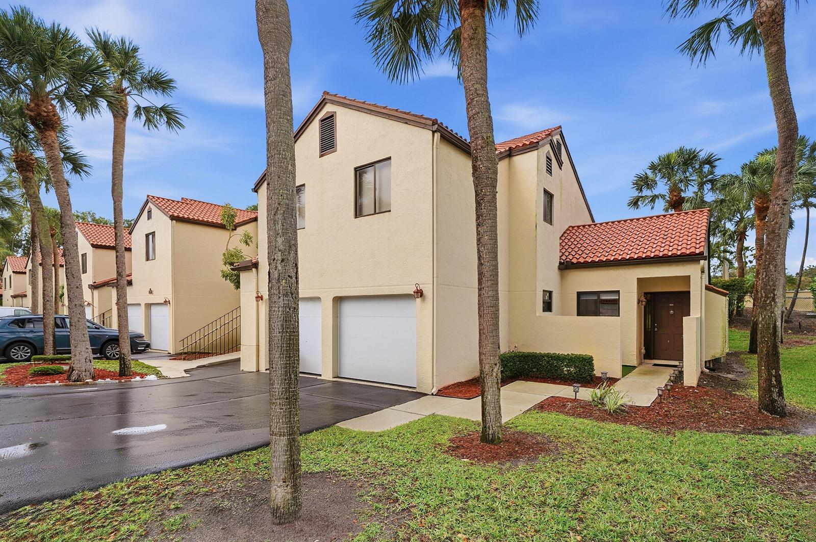 A two-story tan stucco townhouse with a red tile roof and an attached garage — 5 Via De Casas Sur # 105, Boynton Beach FL 33426, BOYNTON BEACH, FL