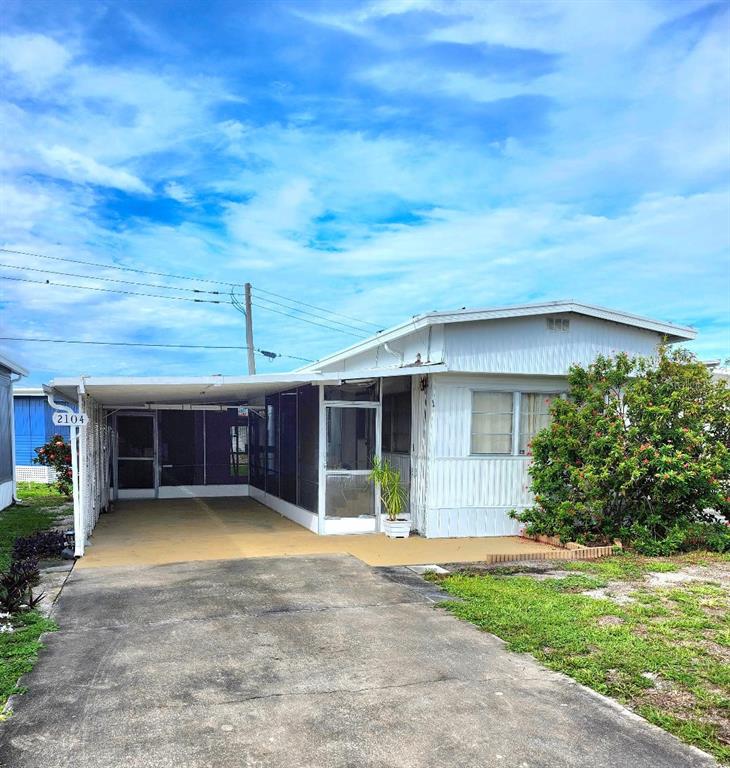 A single-story mobile home with a carport, screened-in porch, and a concrete driveway — 2104 OHIO AVENUE, BRADENTON, FL