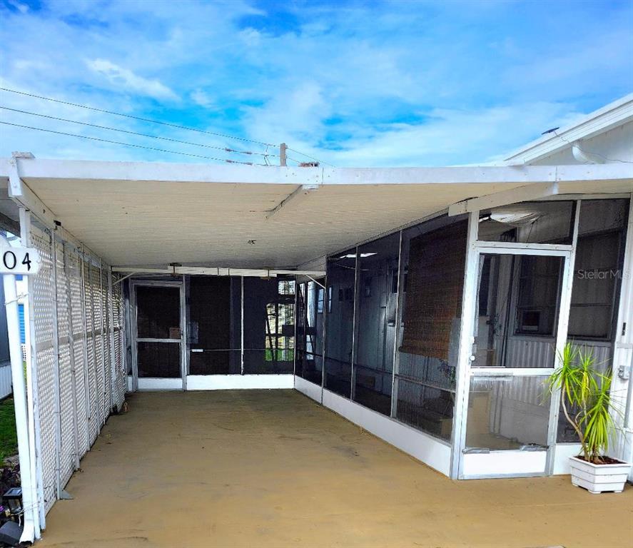 A covered carport with a concrete floor and screened-in walls attached to a house — 2104 OHIO AVENUE, BRADENTON, FL