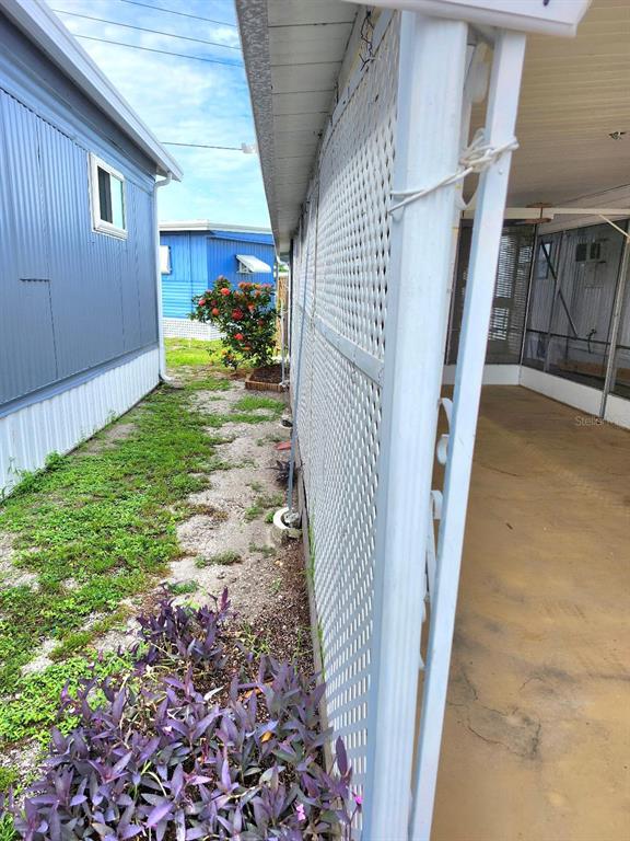 A narrow side yard between two mobile homes features a lattice screen and purple plants — 2104 OHIO AVENUE, BRADENTON, FL