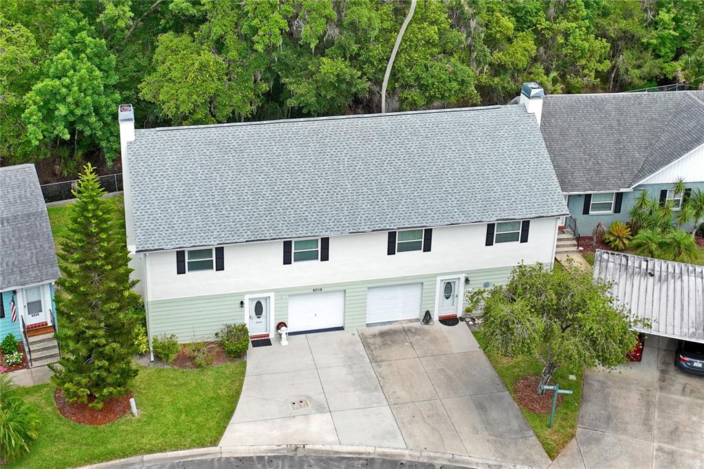 An aerial view shows a two-story duplex with a gray shingled roof and concrete driveways — 6016 WILDS DR, NEW PORT RICHEY, FL