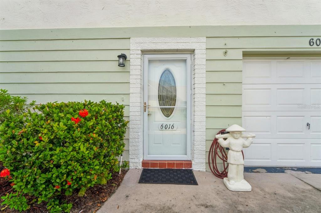 The exterior view shows a front door with a glass insert, a garage, and landscaping — 6016 WILDS DR, NEW PORT RICHEY, FL