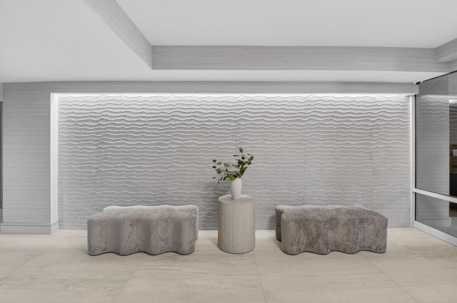 A modern lobby features a textured wave-patterned wall, two upholstered benches, and a central pedestal — 2220 S Ocean Boulevard # 304, Delray Beach FL 33483, DELRAY BEACH, FL