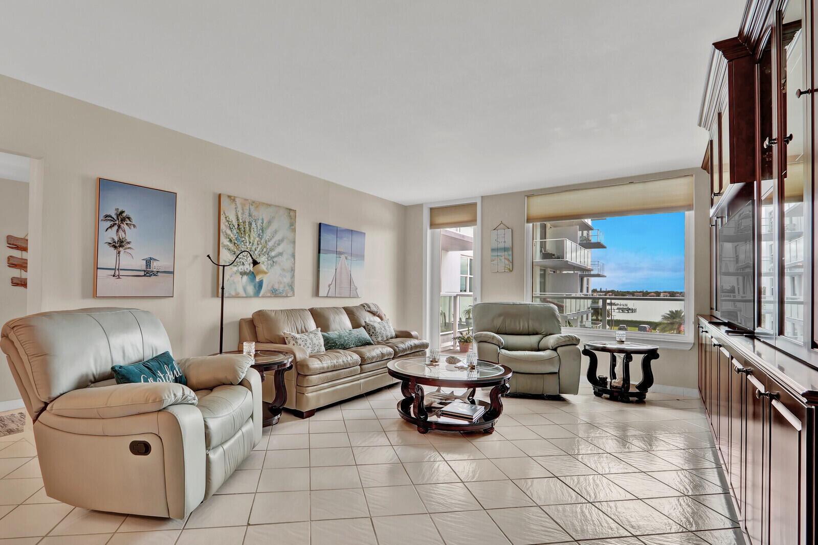 A living room with tile floors, leather furniture, and a large window overlooking the water — 3450 S Ocean Boulevard # 327, Palm Beach FL 33480, PALM BEACH, FL