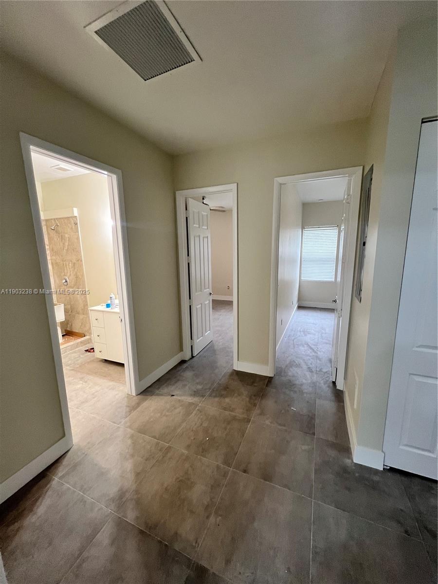 A hallway with tile flooring leads to a bathroom and two additional rooms — 10274 SW 180th St # 1, Miami FL 33157, MIAMI, FL