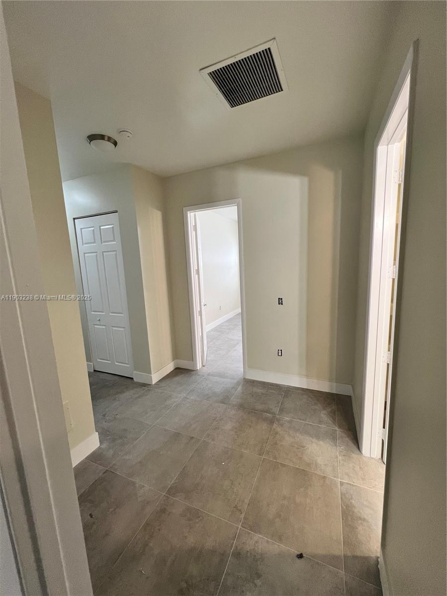 A hallway with gray tile flooring leads to an open doorway and a closed door — 10274 SW 180th St # 1, Miami FL 33157, MIAMI, FL