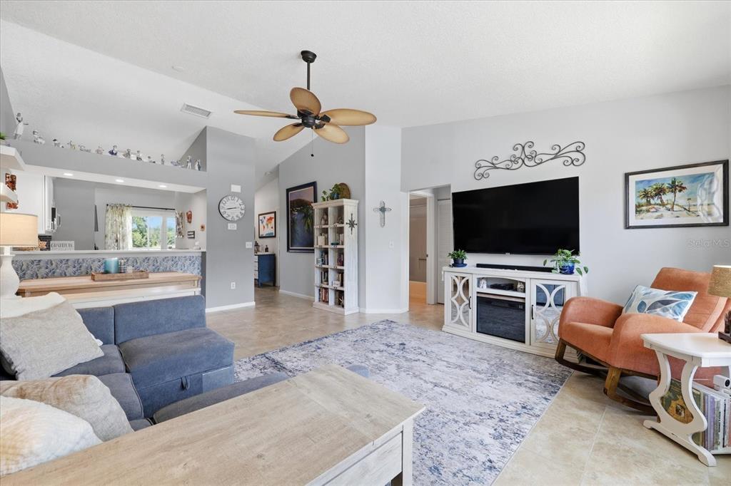 A living room features a blue sectional sofa, a television, and an orange rocking chair — 2240 GULF VIEW BOULEVARD, DUNEDIN, FL