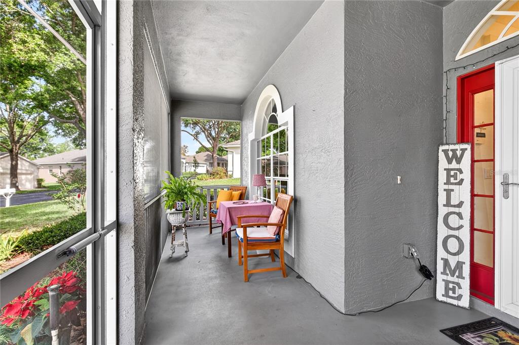 A covered porch features a small table with two chairs, a potted plant, and a door — 3739 HASTING LANE, CLERMONT, FL