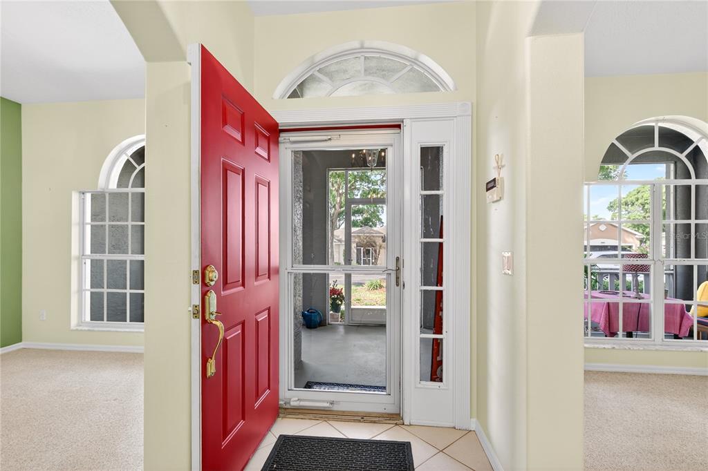 A bright entryway features a red front door, a storm door, and arched windows — 3739 HASTING LANE, CLERMONT, FL