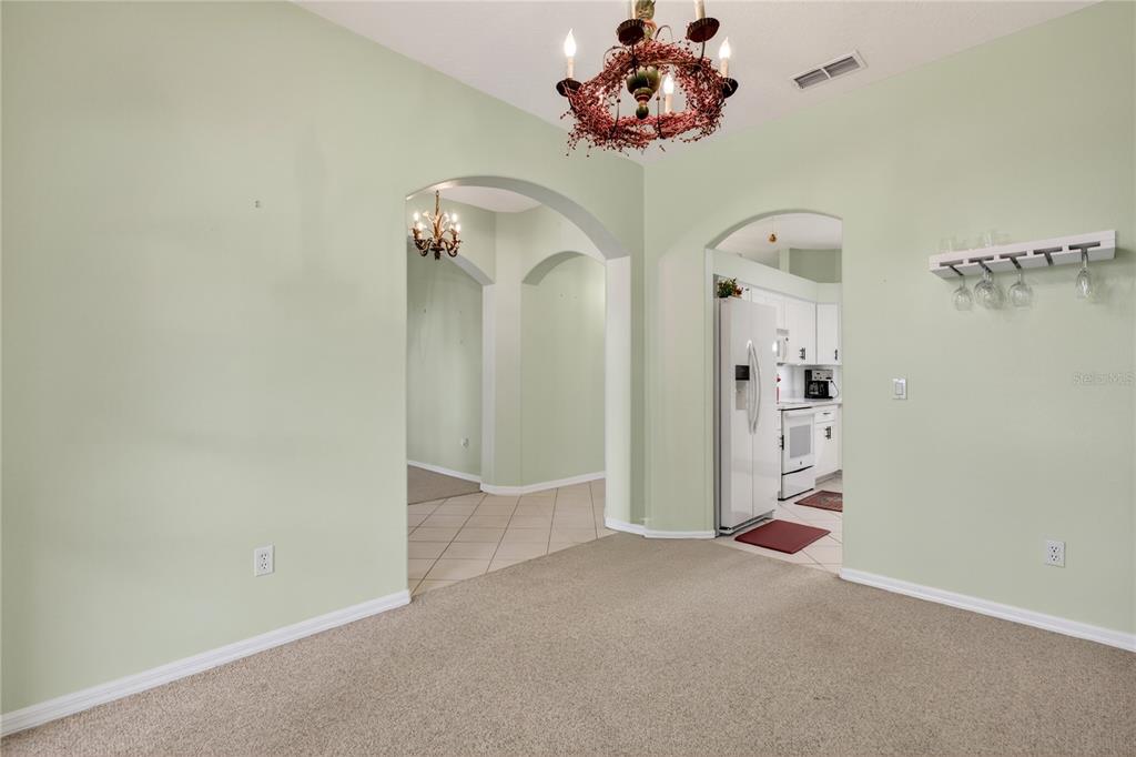 A dining room with light green walls, tan carpet, and a decorative chandelier — 3739 HASTING LANE, CLERMONT, FL