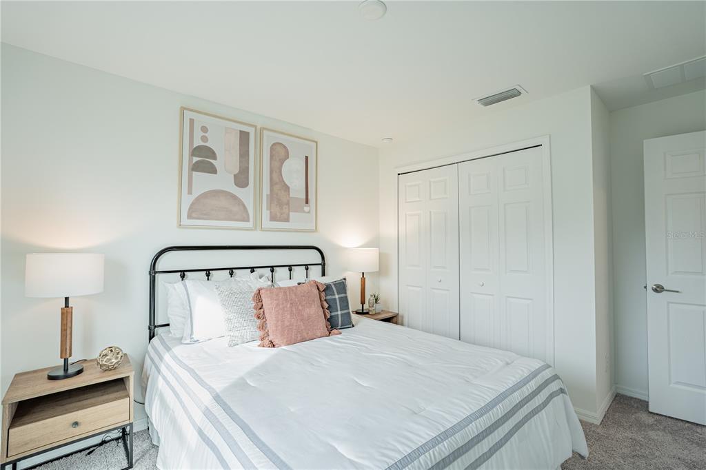 A bedroom features a bed with a black metal frame, two nightstands, and wall art — 2022 LUCKY STREET, PORT CHARLOTTE, FL