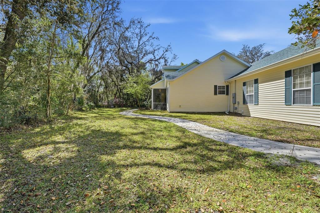 A side view of a yellow house with a concrete walkway leading to a screened porch — 35015 RADIO ROAD, LEESBURG, FL