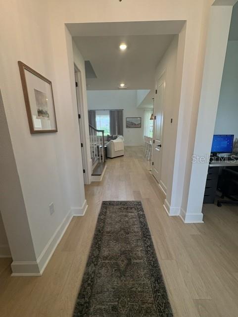 A hallway with light wood flooring leads to an open living area with white walls — 8532 GOLDEN DAWN COURT, SARASOTA, FL