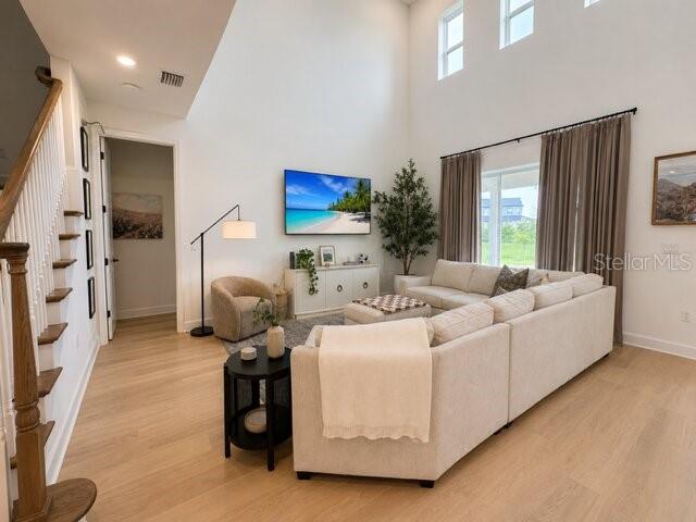 A bright living room features a large sectional sofa, a television, and light wood flooring — 8532 GOLDEN DAWN COURT, SARASOTA, FL