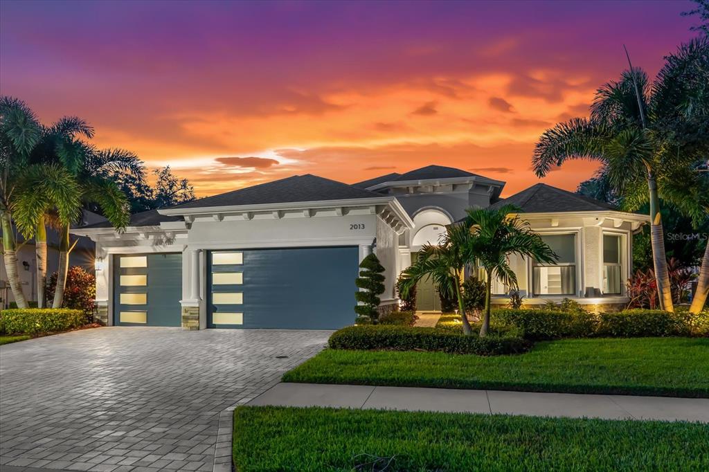 A single-story house with a three-car garage and a paved driveway at sunset — 2013 BEE BRANCH COURT, PALM HARBOR, FL