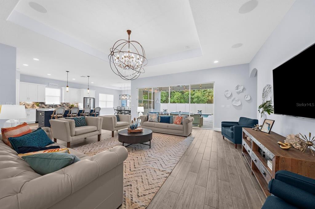 A spacious living room with tile floors, a tray ceiling, and an open kitchen view — 2013 BEE BRANCH COURT, PALM HARBOR, FL